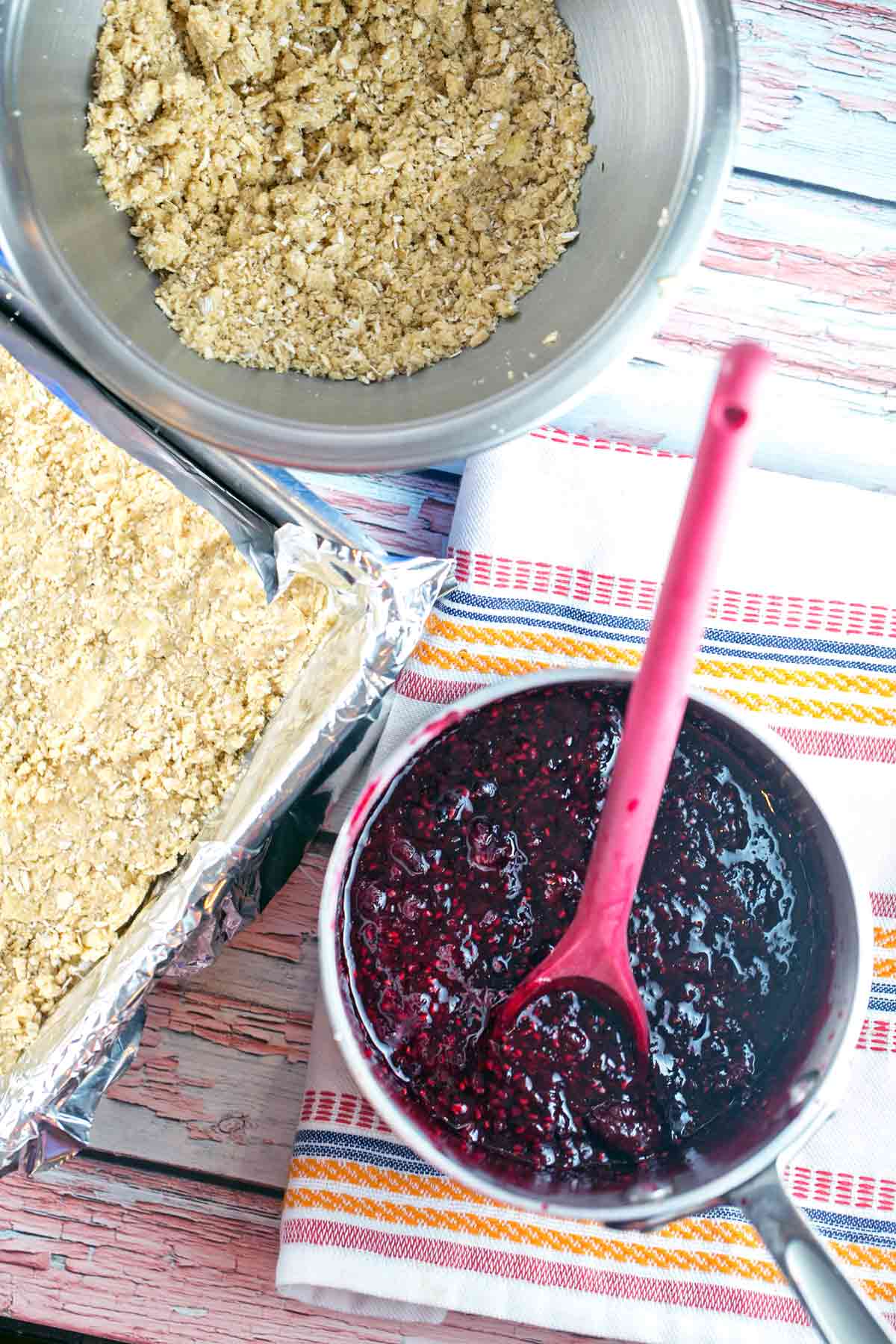 homemade berry jam next to a mixing bowl filled with oatmeal crumble