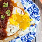 runny egg on a fried tortilla next to black beans and salsa.