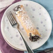 homemade cannoli filled with ricotta on a speckled dessert plate