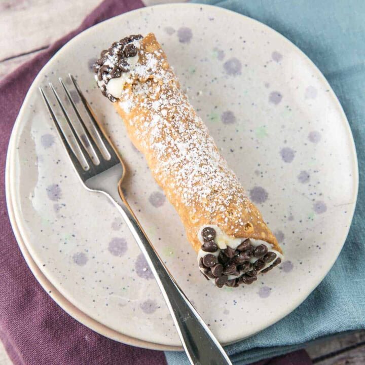 homemade cannoli filled with ricotta on a speckled dessert plate