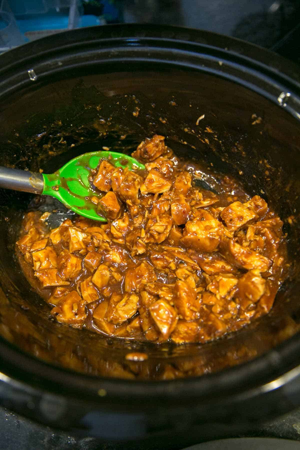 cubes of chicken breast in a slow cooker covered with sauce