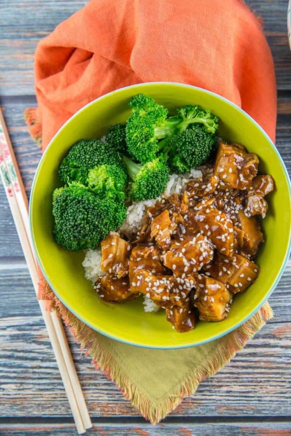 a green bowl filled with slow cooker sesame honey chicken, bright green broccoli, and rice