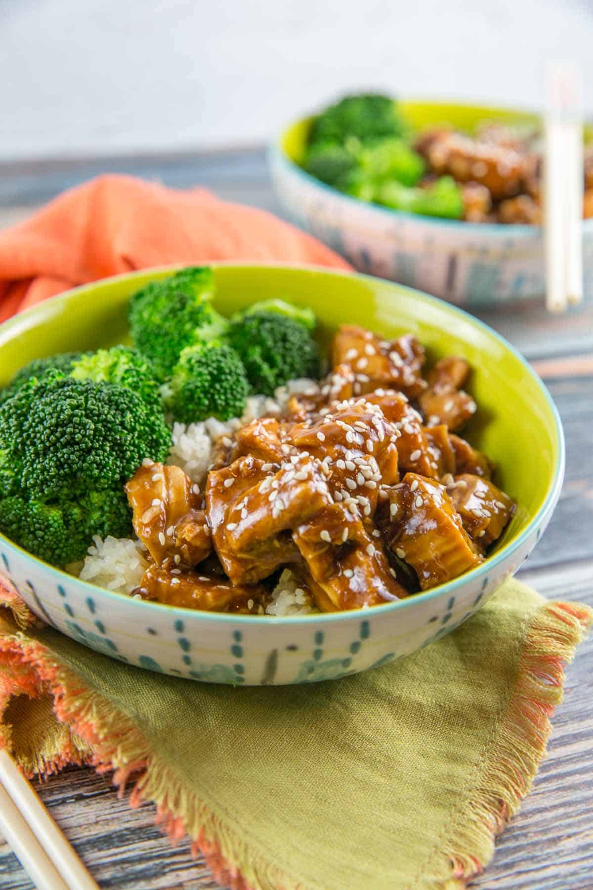 two decorative bowls filled with chicken, broccoli, and rice