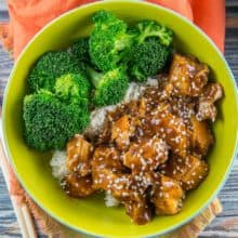 honey sesame chicken in a bowl with steamed broccoli