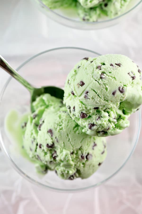 two scoops of green mint chocolate chip ice cream in a glass bowl