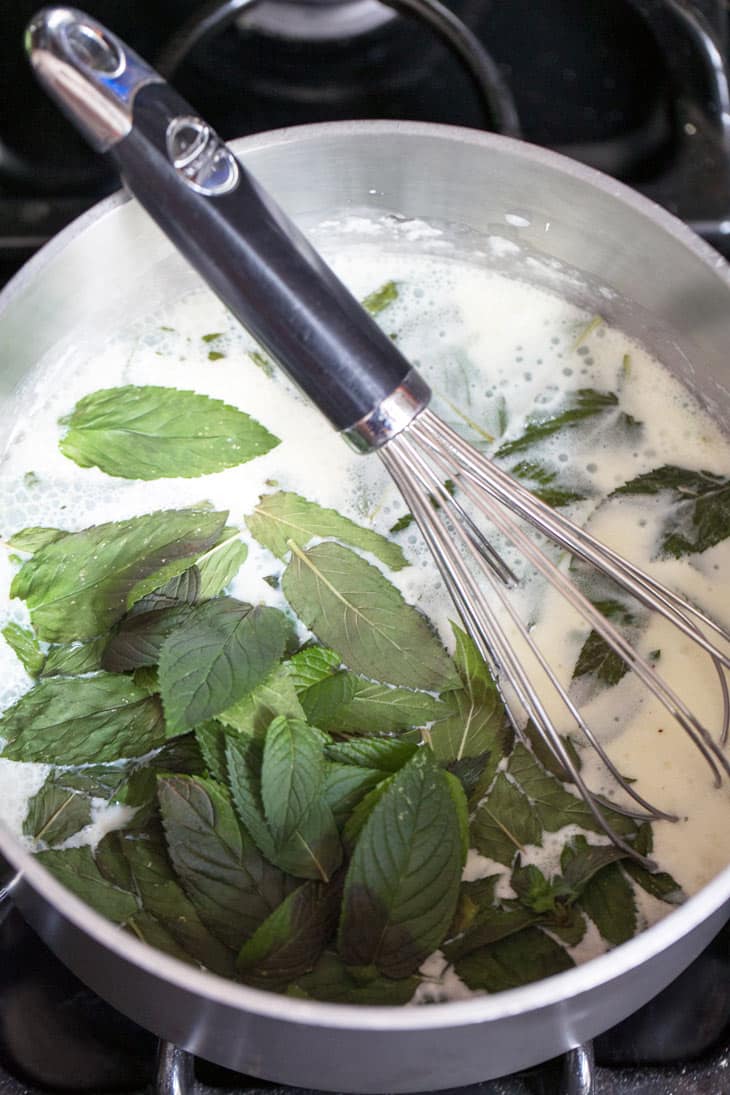 mint leaves seeping in warm milk in a sauce pan