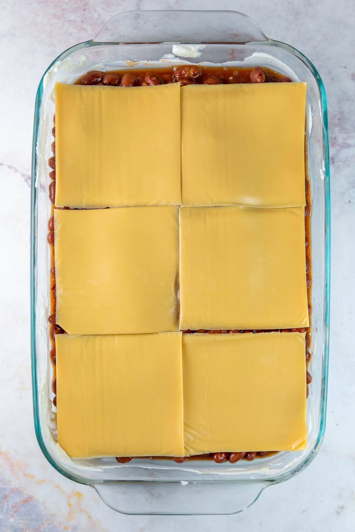 velveeta slices on top of a baking dish filled with beans