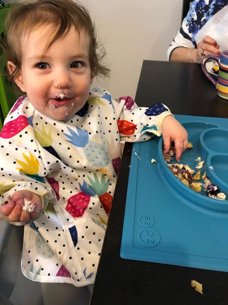 12 month old eating blintzes with a big smile