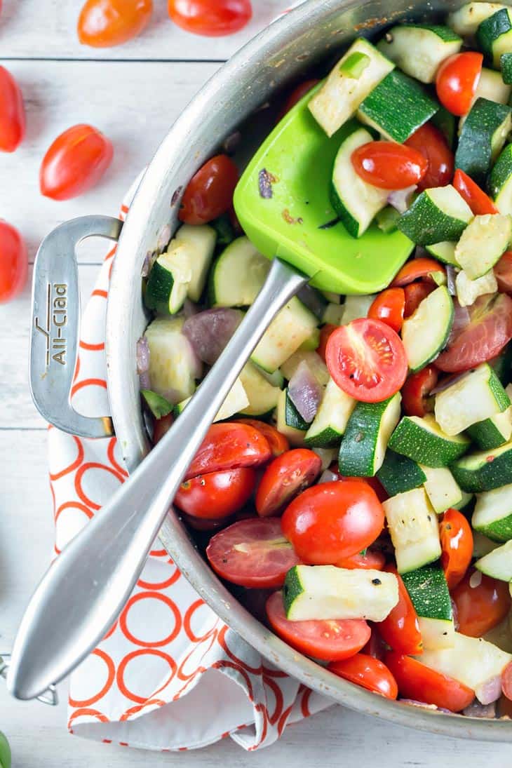 skillet filled with raw zucchini, cherry tomatoes, and red onion