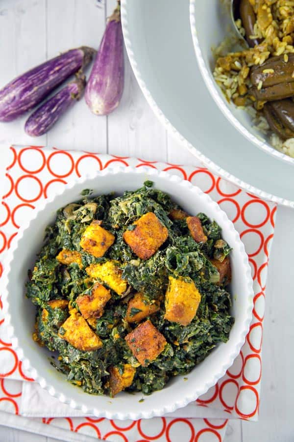saag paneer in a bowl next to indian eggplant curry