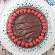 round flourless chocolate cake covered with ganache and raspberries