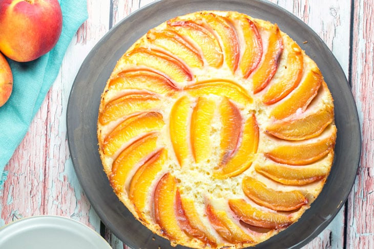 cake on a gray plate covered with a spiral of nectarine slices