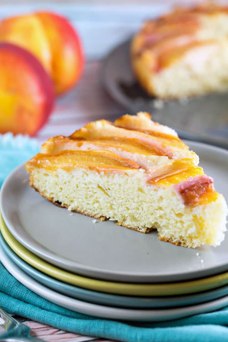 a slice of an upside down nectarine cake on a stack of small dessert plates