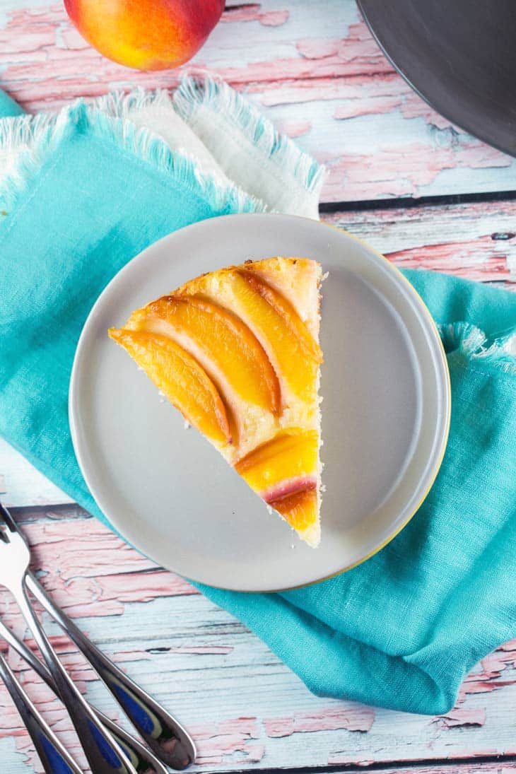 slice of nectarine cake on a gray plate with a blue napkin