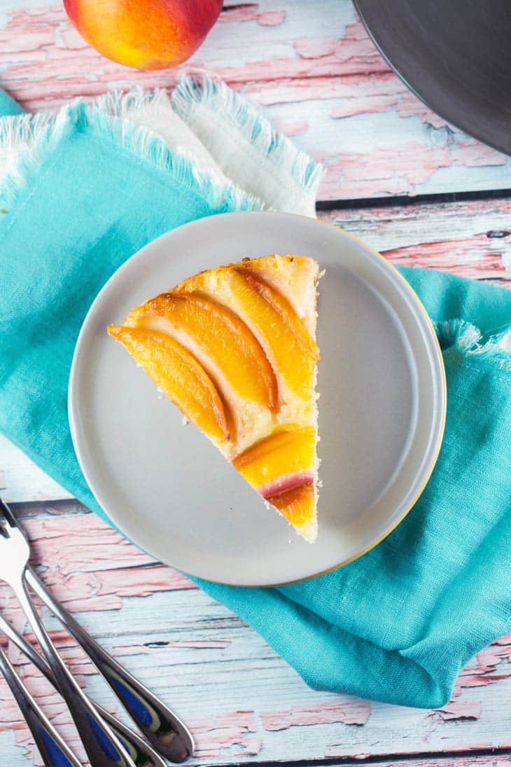 slice of nectarine cake on a gray plate with a blue napkin