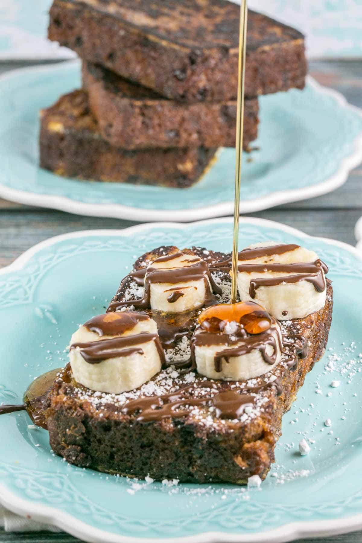 maple syrup being poured from above onto a slice of french toast.