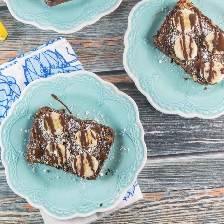 two slices of banana bread french toast covered with chocolate and banana slices.