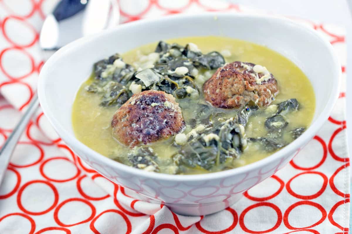 italian wedding soup in a white bowl on a red and white placemat