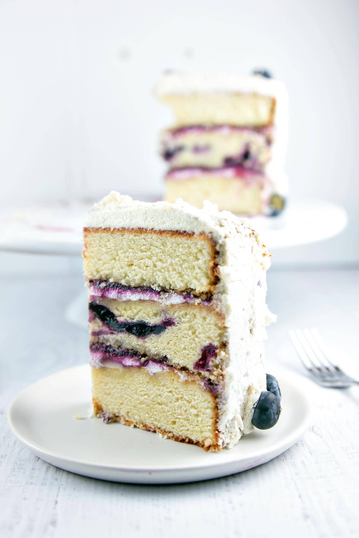 Vanilla Layer Cake with Blueberry Cardamom Curd: A three-layer blueberry vanilla cake filled with blueberry cardamom curd and covered with whipped cream. Simple flavors combine to make a spectacular dessert! {Bunsen Burner Bakery}