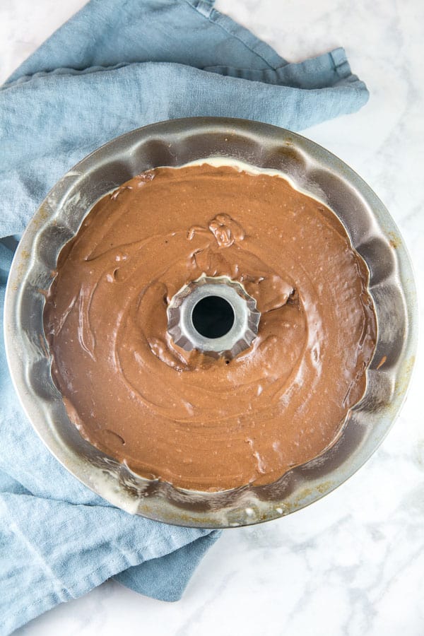 chocolate cake batter in a bundt pan on a blue dish cloth