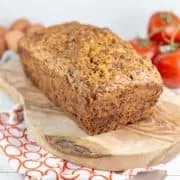 loaf of tomato bread with tomatoes and eggs in the background