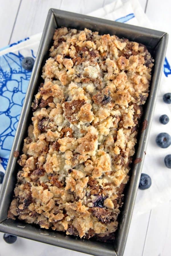 a loaf of blueberry pie bread in the loaf pan covered with a toasted almond crumble