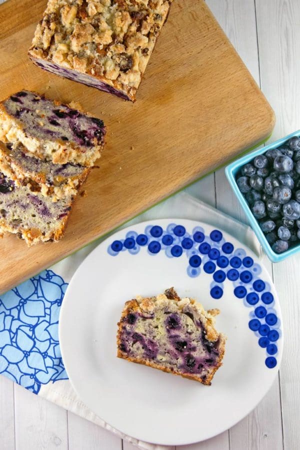 a slice of purple swirled blueberry pie bread on a decorative blueberry plate