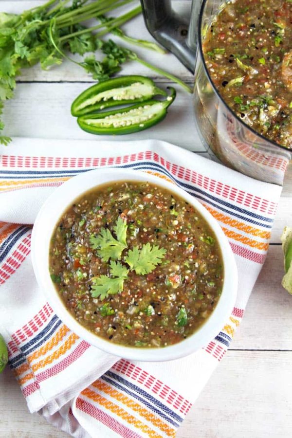 homemade roasted tomatillo salsa verde in a white serving dish on a colorful dishtowel