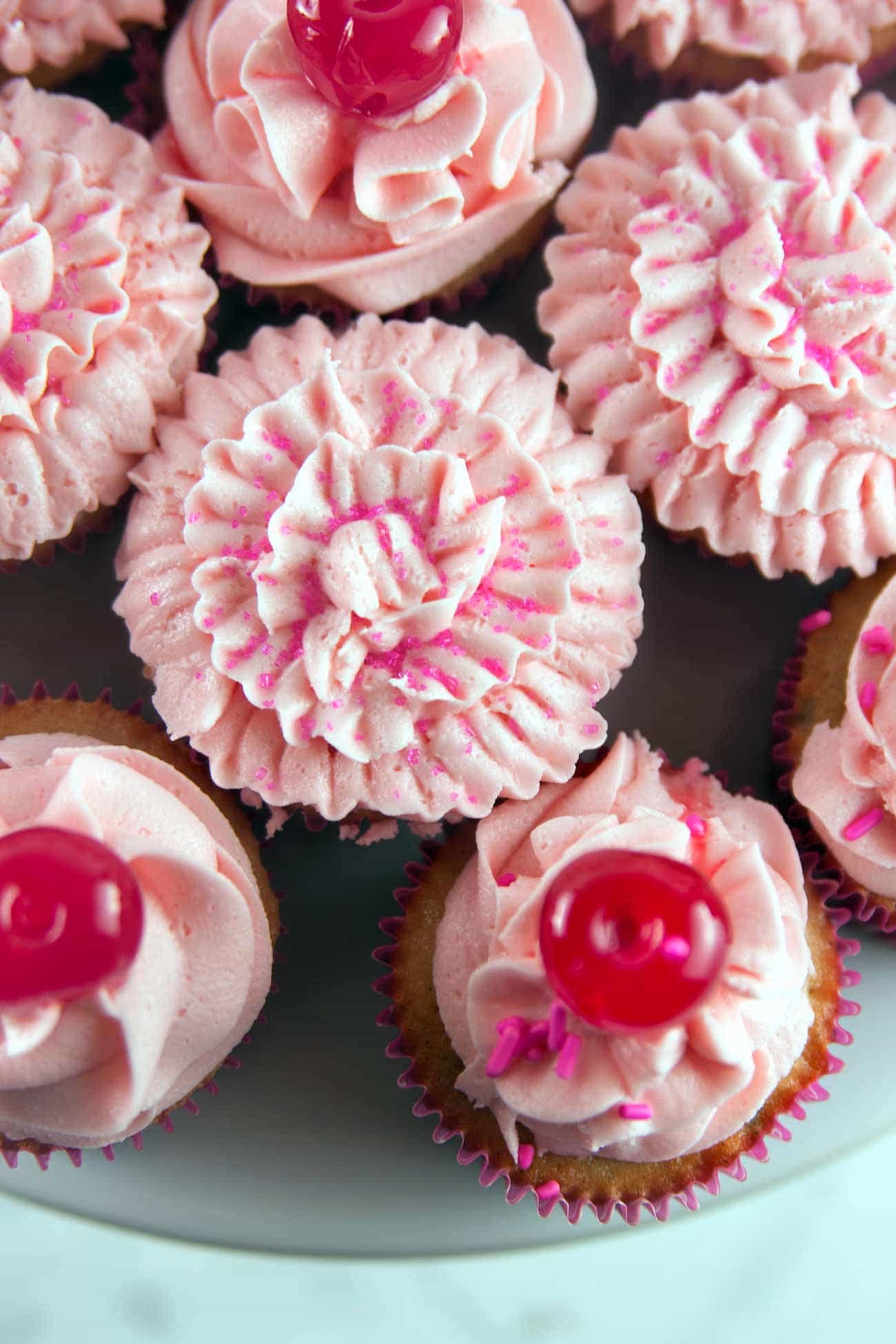 Chocolate Chip Cherry Cupcakes: vanilla-speckled cupcakes studded with mini chocolate chips and a pile of fluffy cherry buttercream. Top with a cherry - or bake one right inside! {Bunsen Burner Bakery}