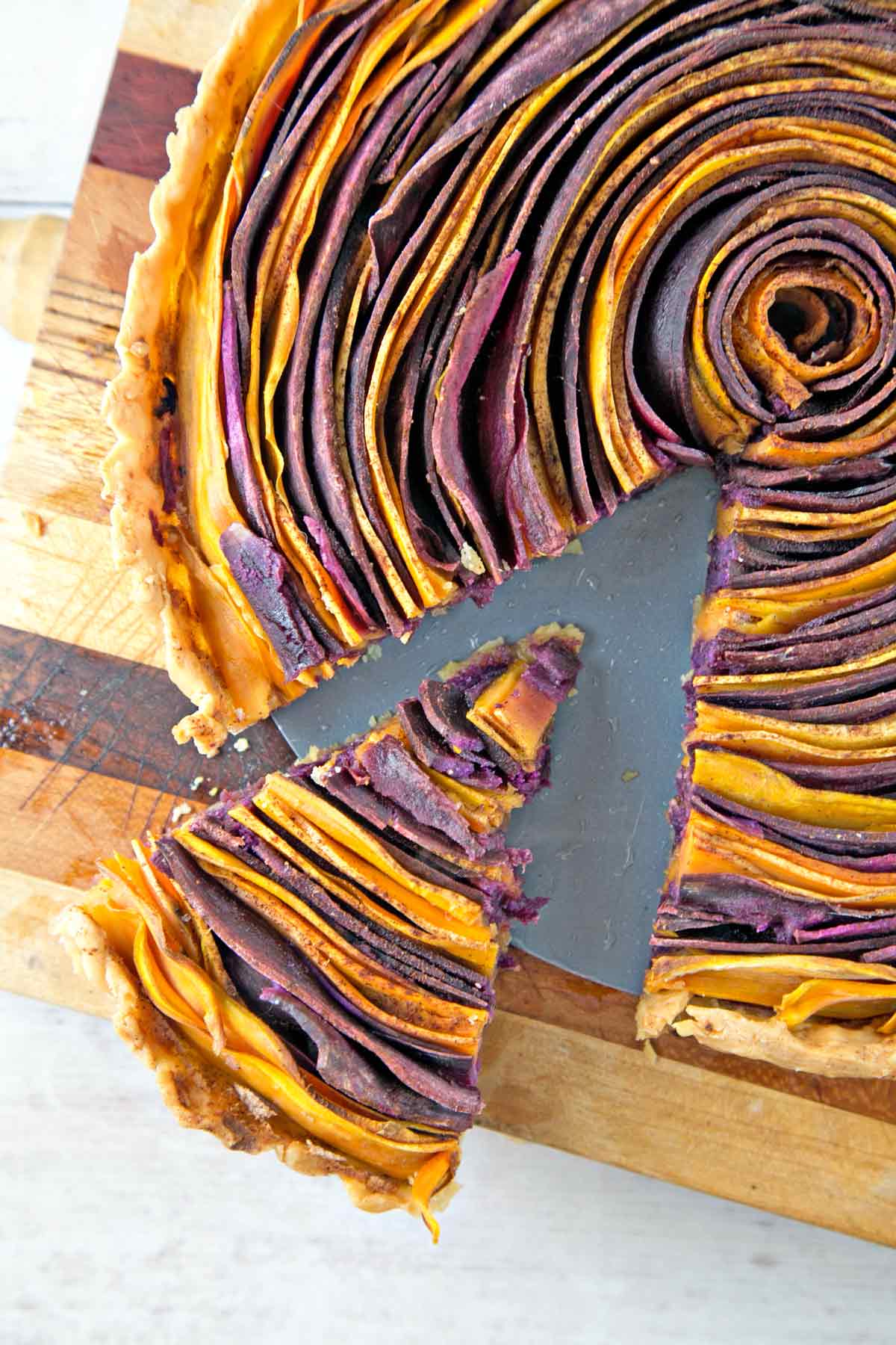 one slice cut and slightly removed from a spiral sweet potato tart with whipped maple ricotta