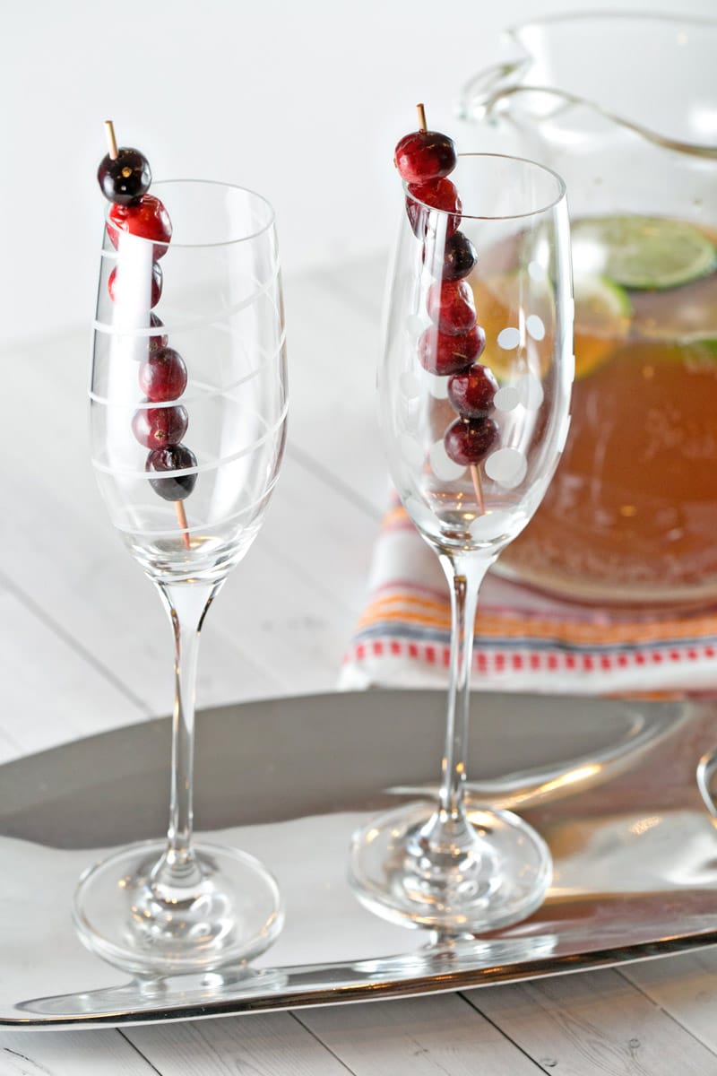 two champagne glasses with skewers of fresh cranberries.