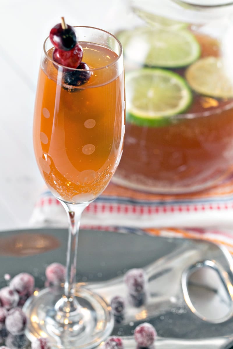 glass of cranberry apple cider champagne punch on a tray with sugared cranberries.