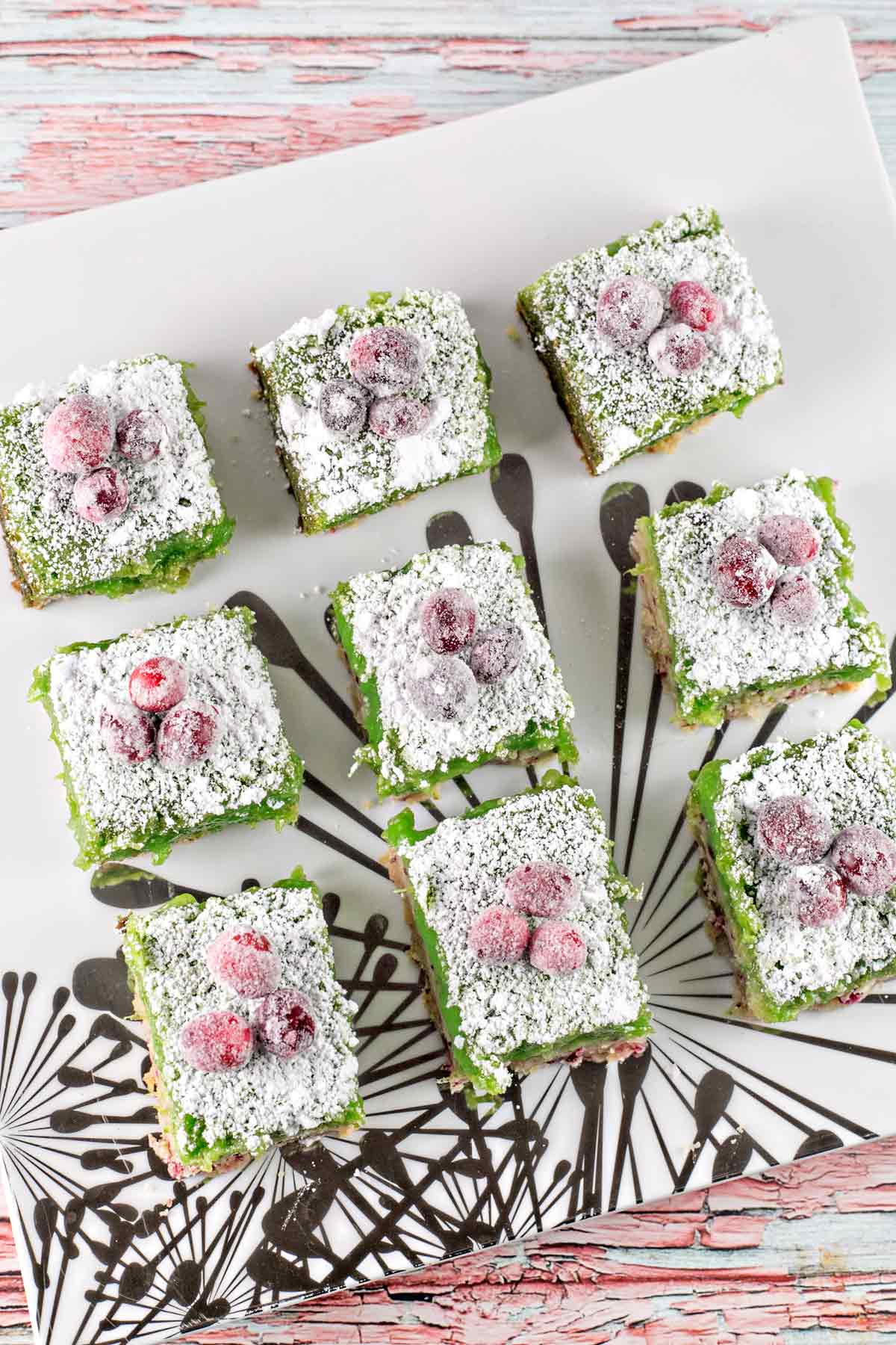 cranberry lime bars topped with sugared cranberries arranged on a serving dish.