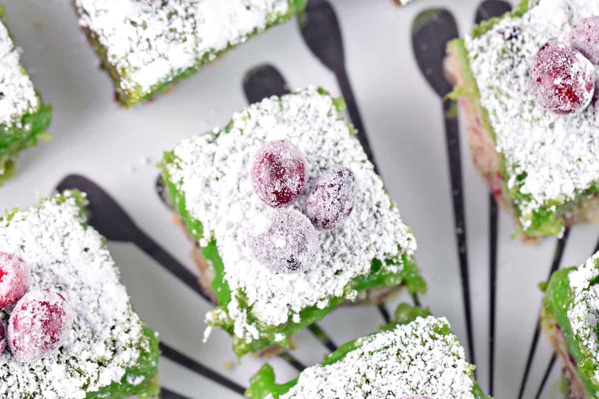 lime bars with cranberry shortbread dusted with powdered sugar and topped with sugared cranberries.