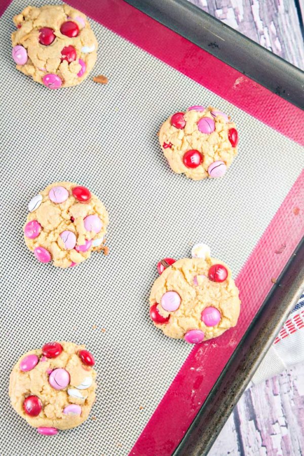 freshly baked m&m cookies on a silicone-lined baking sheet.