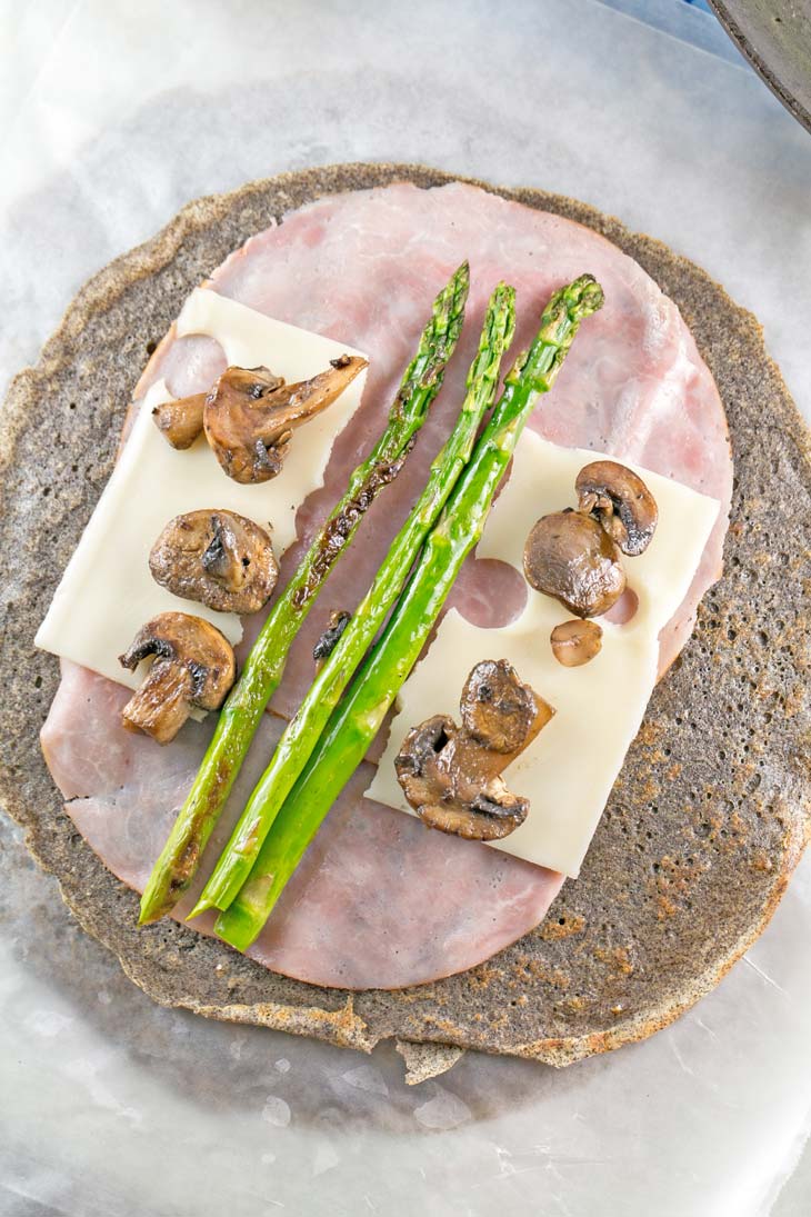 Ham and Asparagus Crepe Rolls made with buckwheat crepes, two slices of ham, a slice of cheese, asparagus, and sliced mushrooms.