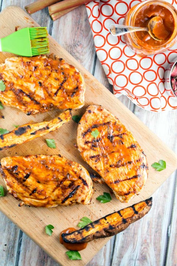a wooden board with grilled chicken breasts and sweet potatoes with chipotle rhubarb bbq sauce