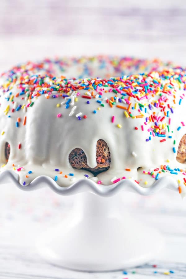 a sprinkle covered bundt cake with a thick white vanilla glaze