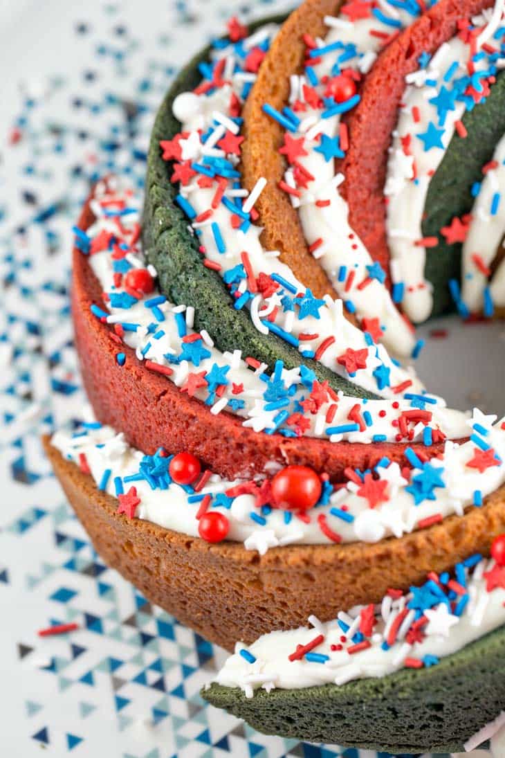 close up view of a bundt cake showing the thick vanilla glaze covered in festive sprinkles