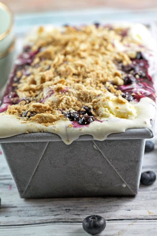 frozen blueberry pie ice cream layered in a loaf pan with vanilla ice cream, blueberry pie filling, and graham cracker crumbs