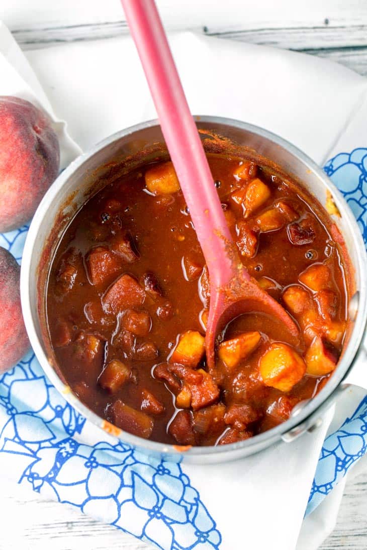 peaches and tomatoes cooking down in a sauce pan to make BBQ sauce