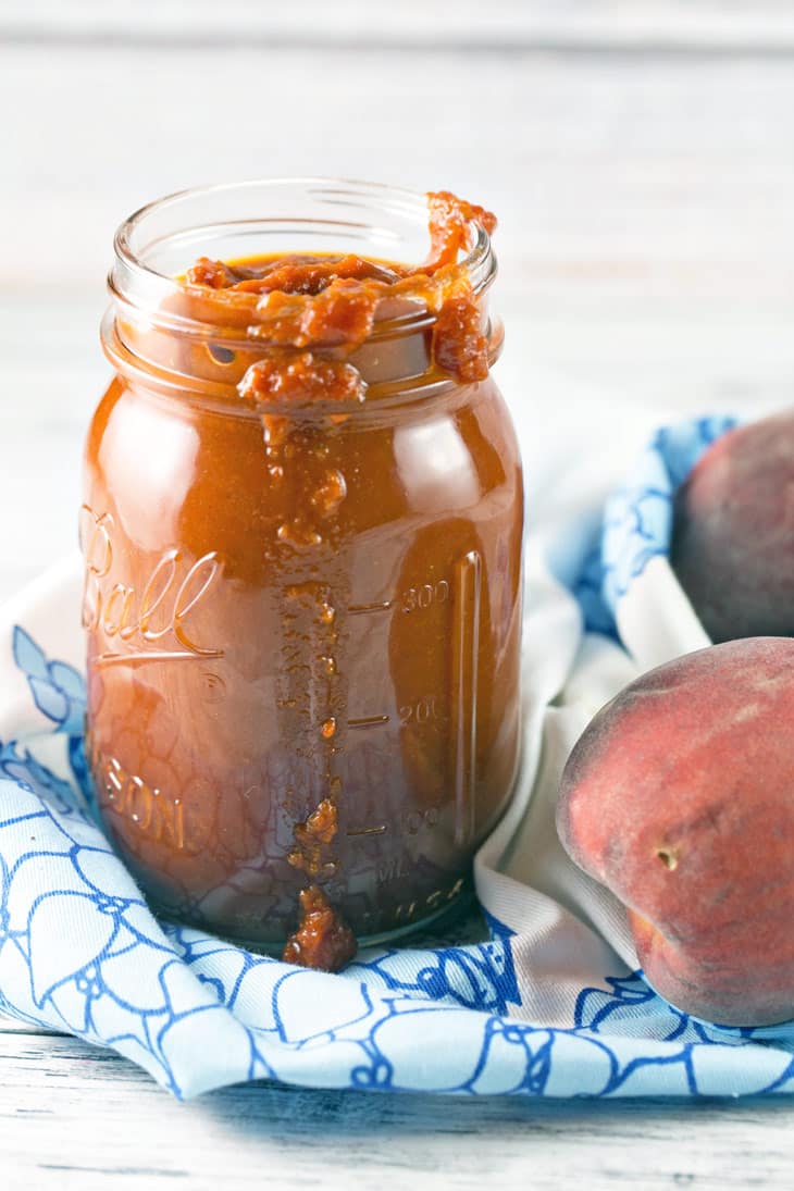 a glass mason jar with barbecue sauce dripping down the side