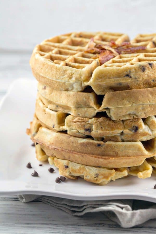 five bacon chocolate chip waffles stacked on a white plate