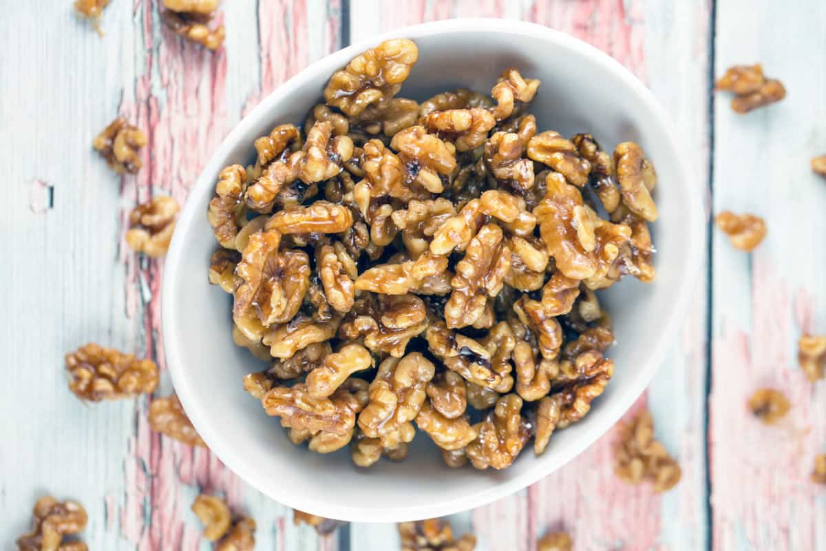 overhead photo of white bowl filled with maple glazed walnuts.