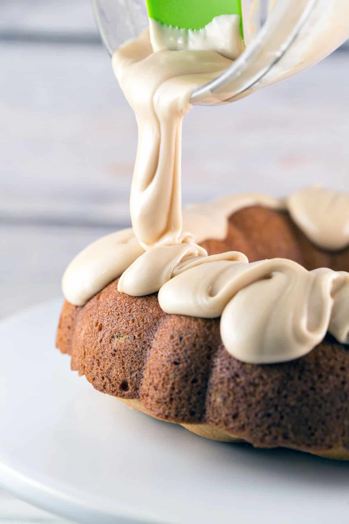 side view of pouring maple frosting over a bundt cake