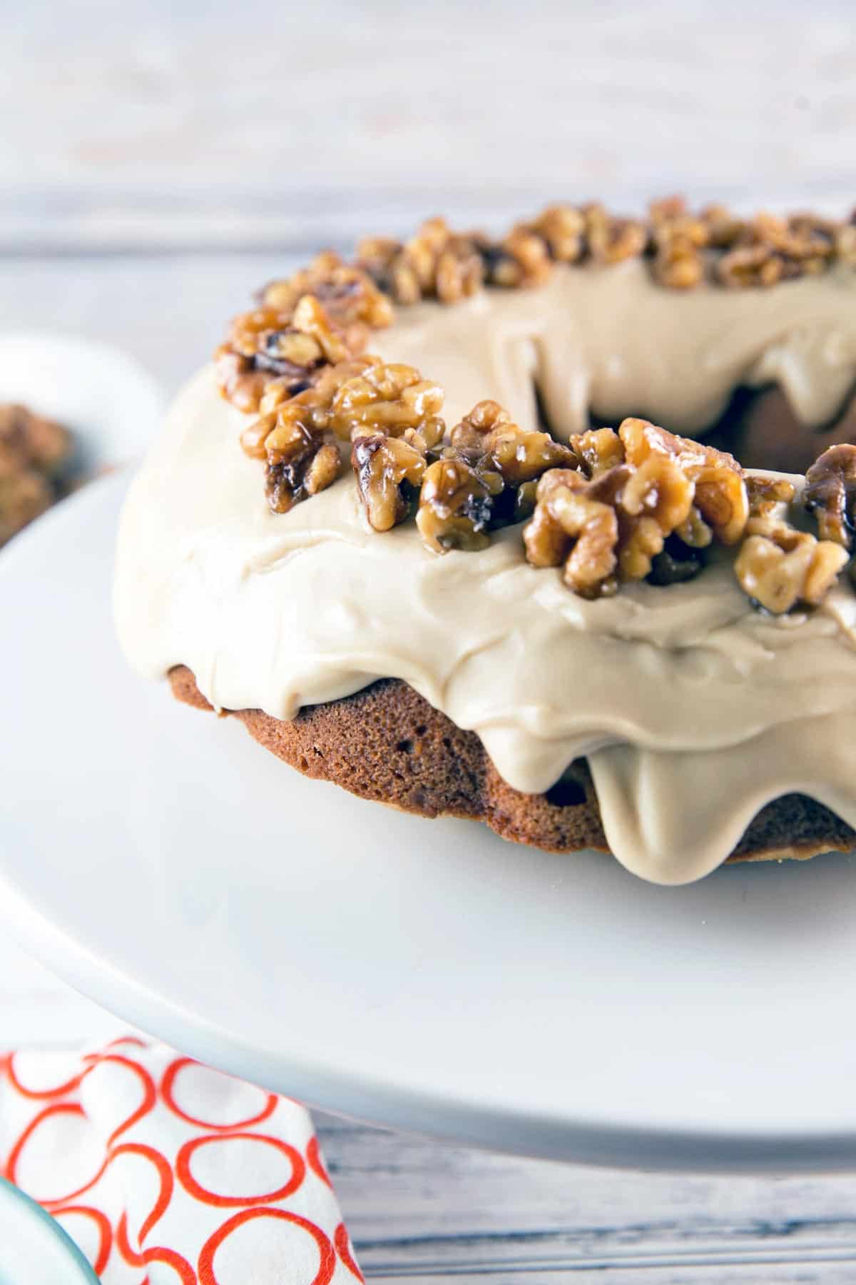 bundt cake covered in maple frosting with maple glazed walnuts on top