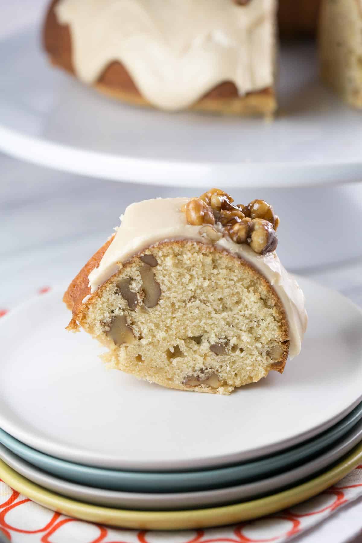 one slice of maple walnut bundt cake on a stack of dessert plates