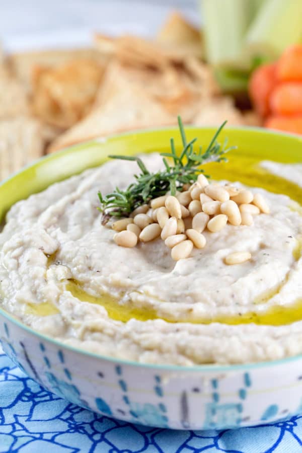 close up view of pine nuts and rosemary piled on top of easy gluten-free bean dip