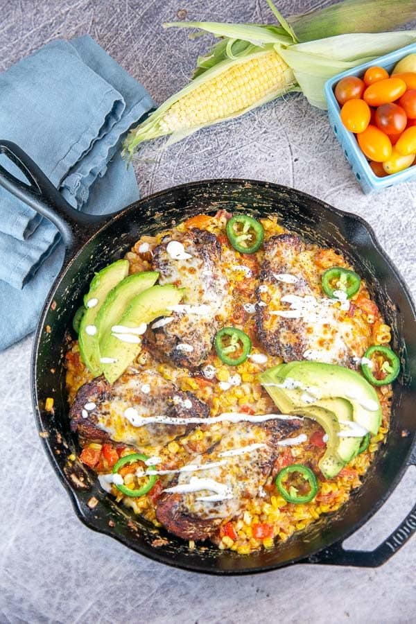 cast iron skillet with chicken topped with avocados and jalapenos