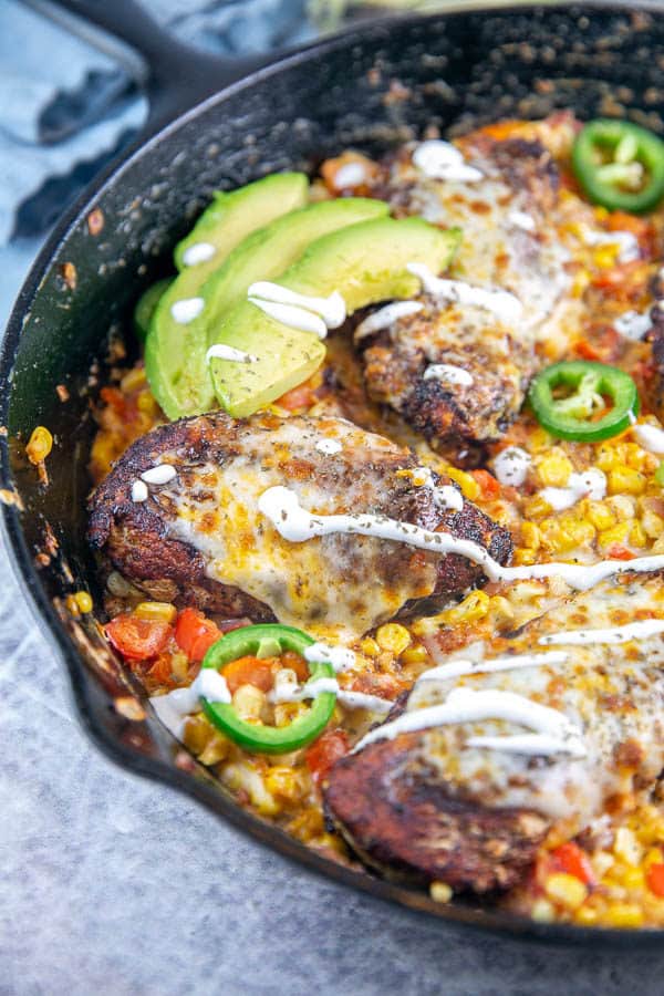 cast iron chicken skillet dinner with avocados and drizzled sour cream